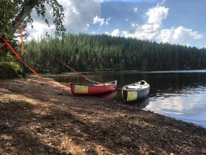 two boats are docked on the shore of a lake at Mieps Huset Dalarna Holiday in Kullen