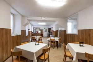 a dining room with white tables and wooden walls at Ostello di Germagno in Omegna