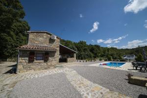 een stenen huis met een zwembad en een gebouw bij Holiday Home Cosseriga in Račički Brijeg