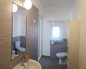 a bathroom with a sink and a toilet and a mirror at Hóvirág Apartman Balatonberény in Balatonberény