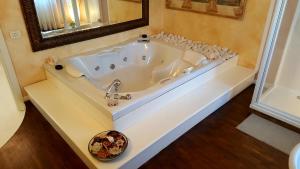 baño con bañera blanca grande y espejo en B&B Villa Fiorini en Moniga