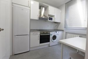 a kitchen with white cabinets and a washer and dryer at Acogedor Apartamento en Santander in Santander