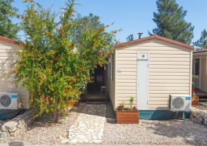 a house with a large orange tree next to a building at Krk Mobile Homes in Klimno