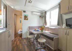 a small kitchen with a table and chairs in a caravan at Krk Mobile Homes in Klimno