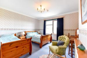 a bedroom with two beds and a chair at Herrislea House Hotel in Tingwall