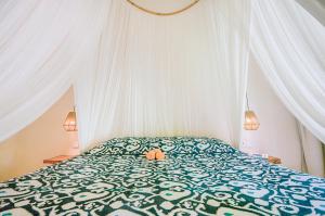 a bedroom with a bed with a green and white comforter at Mule Malu Tropical Stay in Uluwatu
