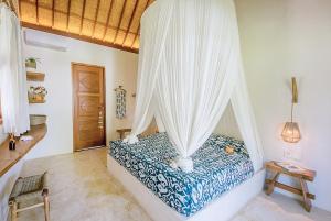 a bedroom with a bed with mosquito netting at Mule Malu Tropical Stay in Uluwatu
