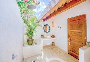 a bathroom with a toilet and a plant in it at Mule Malu Tropical Stay in Uluwatu