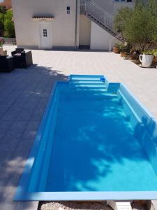 a swimming pool with blue water in front of a building at Holiday House ''Villa Flora'' in Šibenik