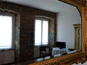 a mirror reflecting a room with a table and two windows at B&B Gens Julia in Trieste