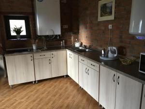 a kitchen with white cabinets and a brick wall at Casa Skandik H&aacute;z in Băile Tuşnad