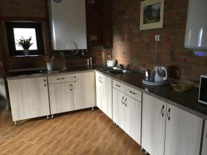 a kitchen with white cabinets and a brick wall at Casa Skandik Ház in Băile Tuşnad