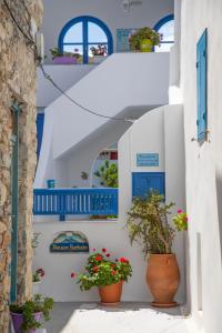 a row of white buildings with blue doors and potted plants at Pension Barbara in Katapola