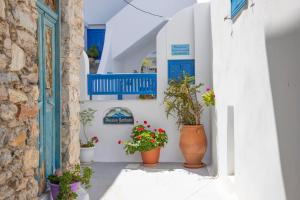 uma rua com paredes brancas e portas azuis e vasos de plantas em Pension Barbara em Katápola