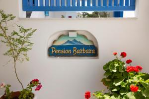 a sign on a wall with flowers and a window at Pension Barbara in Katapola