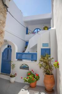 un bâtiment blanc avec des portes bleues et des plantes en pot dans l'établissement Pension Barbara, à Katápola