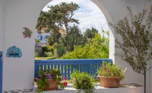 an archway with potted plants and a blue fence at Pension Barbara in Katapola