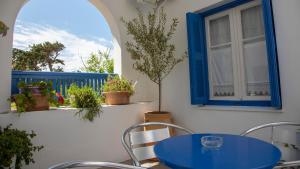 a patio with a blue table and chairs and a window at Pension Barbara in Katapola