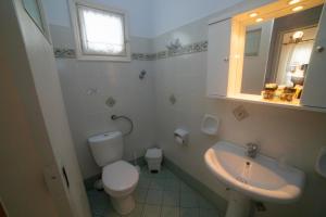 a white bathroom with a toilet and a sink at Pension Barbara in Katapola