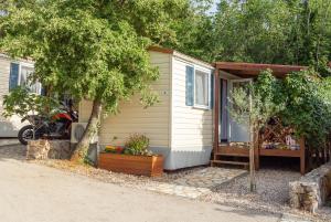 a small house with a motorcycle parked next to it at Krk Mobile Homes in Klimno