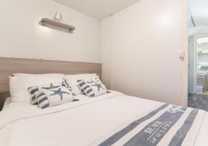 a bedroom with a white bed with blue and white pillows at Krk Mobile Homes in Klimno