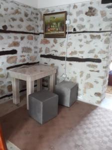 uma mesa e duas caixas num quarto com uma parede de pedra em Bona's Home em Tushemisht