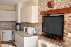 a kitchen with a brick wall with a flat screen tv at Les Weitchiis in Veyrier-du-Lac