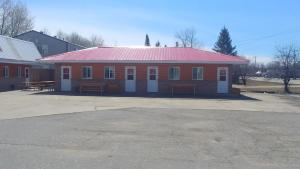 a red building with a red roof with benches in front at Falls Motel in International Falls