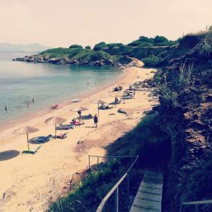 uma praia com guarda-sóis e pessoas na areia em Iraklis Hotel em Mitikas