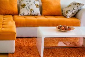 a living room with a couch and a bowl of fruit on a table at Apartments Harmonia Colours in Budva