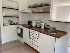 eine kleine Küche mit einer Spüle und einer Mikrowelle in der Unterkunft B&B Apartment Rødekro in Rødekro