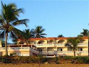 a large building with palm trees in front of it at Luquillo Sunrise Beach Inn in Luquillo