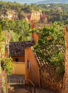 een uitzicht op een berg met gebouwen en bomen bij La goutte d'or in Roussillon