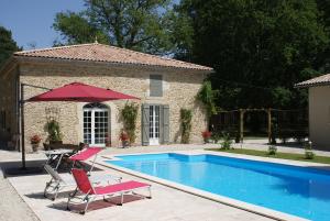 una piscina con due sedie e un ombrellone di DOMAINE DU BOIS SEGUIN a Saint-Loubert