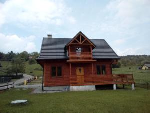 a log cabin with a porch on a field at Apartamenty Kasina in Kasina Wielka