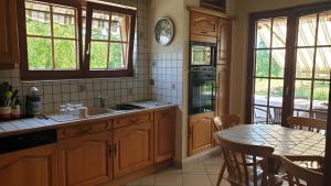 a kitchen with wooden cabinets and a table and a table and chairs at location à la campagne aux portes de Mulhouse in Sausheim