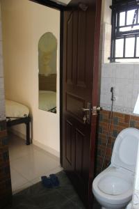 a bathroom with a toilet and a door with a mirror at Tita Tourist Resort in Moroto