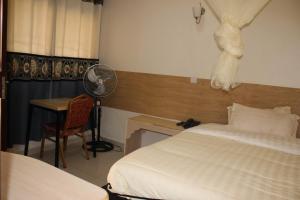 Schlafzimmer mit einem Bett und einem Schreibtisch mit einem Ventilator in der Unterkunft Tita Tourist Resort in Moroto