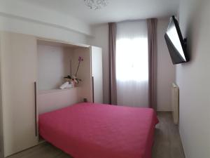 a bedroom with a pink bed and a window at Aurea Rooms in Porto Cesareo