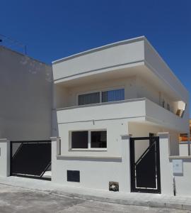 a white house with black gates in front of it at Aurea Rooms in Porto Cesareo