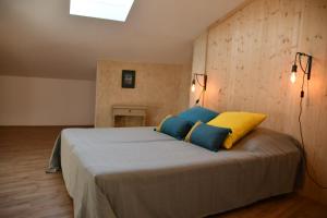a bedroom with a large bed with blue and yellow pillows at Le pigeonnier in Malaucène