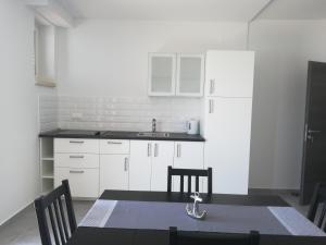 a kitchen with white cabinets and a table and chairs at Villa Adagio Apartments in Sumartin