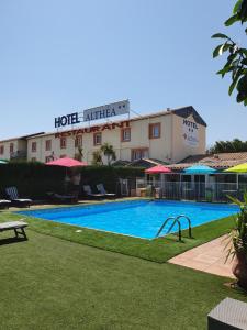 ein Hotel mit einem Pool vor einem Gebäude in der Unterkunft Hôtel Althea - Piscine et Sauna in Béziers