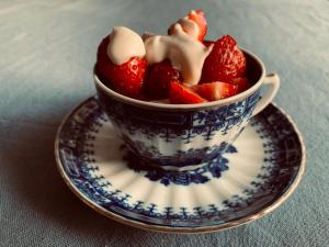 a blue and white cup filled with strawberries on a plate at Ottenson Saaremaa apartment in Salme +21 photos