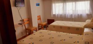 um quarto com duas camas e duas cadeiras e uma televisão em Hostal El Cairo em Ferrol