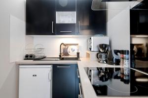 une cuisine avec des armoires et des appareils en noir et blanc dans l'établissement :) Grand studio lumineux à Toulouse et parking, à Toulouse