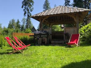 two red chairs and a grill in a yard at Pokoje u Kasi przy Dol. Chochołowskiej in Witów