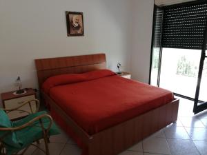 Schlafzimmer mit einem Bett mit einer roten Tagesdecke in der Unterkunft Casa Annamaria in Torre Orsaia