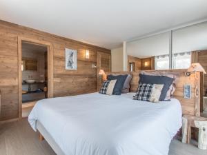 a bedroom with a large white bed and wooden walls at chalet des grands bois in Les Houches