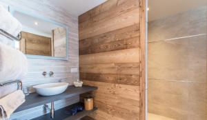 uma casa de banho com um lavatório e uma parede de madeira em chalet des grands bois em Les Houches